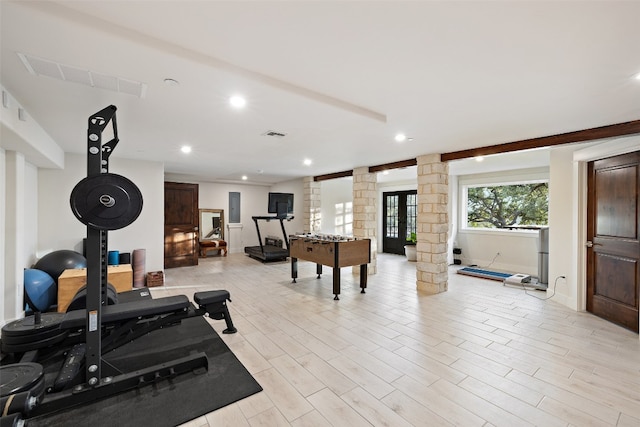 workout room featuring decorative columns and light hardwood / wood-style floors