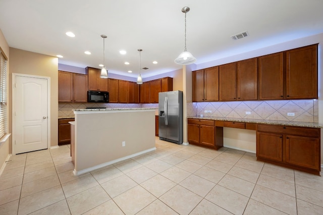 kitchen with decorative light fixtures, stainless steel fridge, light stone countertops, and decorative backsplash