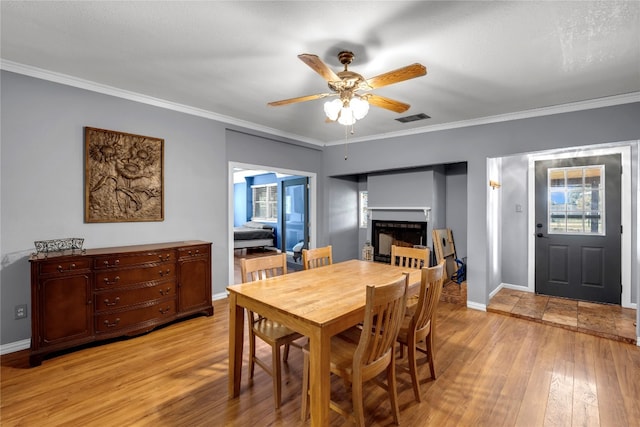 dining room with a healthy amount of sunlight, ceiling fan, ornamental molding, and light hardwood / wood-style floors