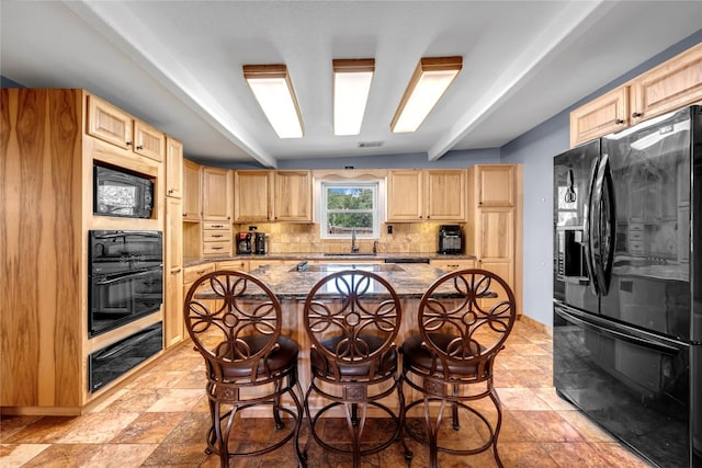 kitchen with a kitchen island, light stone countertops, black appliances, a kitchen bar, and light brown cabinets