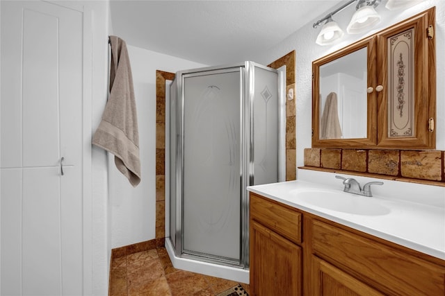 bathroom with a shower with shower door, a textured ceiling, and vanity