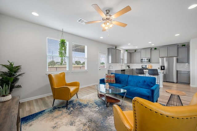 living room with light wood-type flooring and ceiling fan