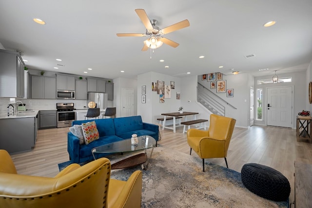 living room featuring sink, ceiling fan with notable chandelier, and light hardwood / wood-style floors