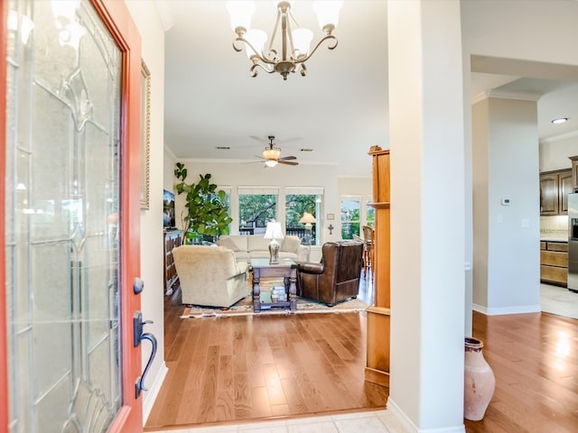 entryway with ceiling fan with notable chandelier, ornamental molding, and light hardwood / wood-style flooring