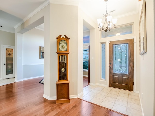 foyer with a chandelier, light hardwood / wood-style floors, and crown molding