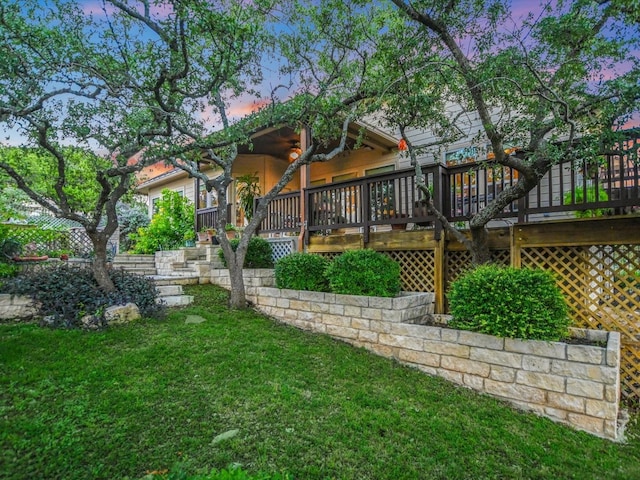 back house at dusk with a wooden deck and a yard