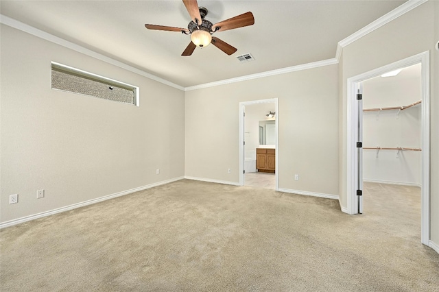 unfurnished bedroom with light carpet, crown molding, a walk in closet, and ceiling fan