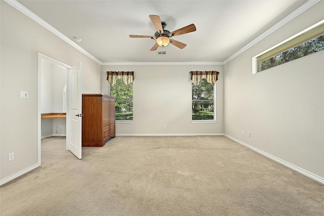 carpeted spare room featuring ceiling fan, a wealth of natural light, and crown molding