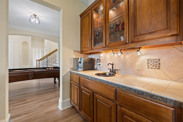 bar with sink, decorative backsplash, ornamental molding, pool table, and light hardwood / wood-style flooring