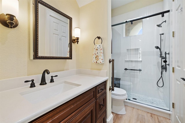 bathroom with hardwood / wood-style flooring, vanity, an enclosed shower, and toilet