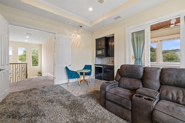 carpeted living room featuring ornamental molding and a tray ceiling