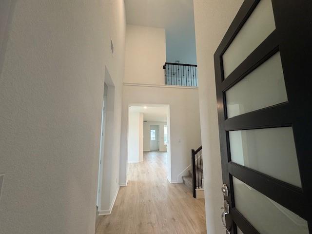 corridor featuring a high ceiling and light hardwood / wood-style flooring