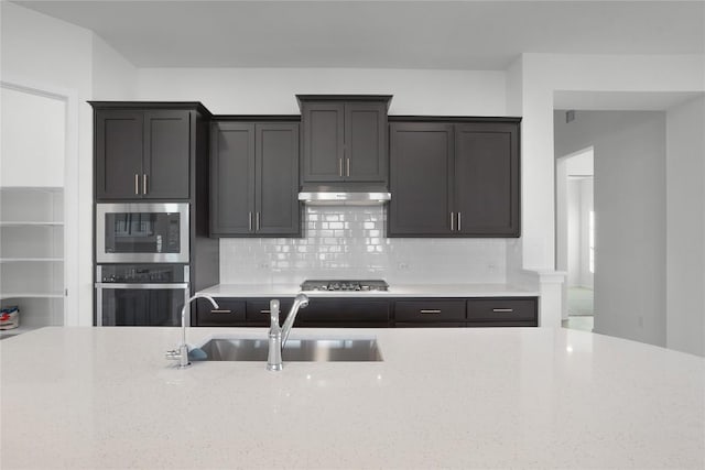 kitchen featuring light stone counters, sink, and appliances with stainless steel finishes