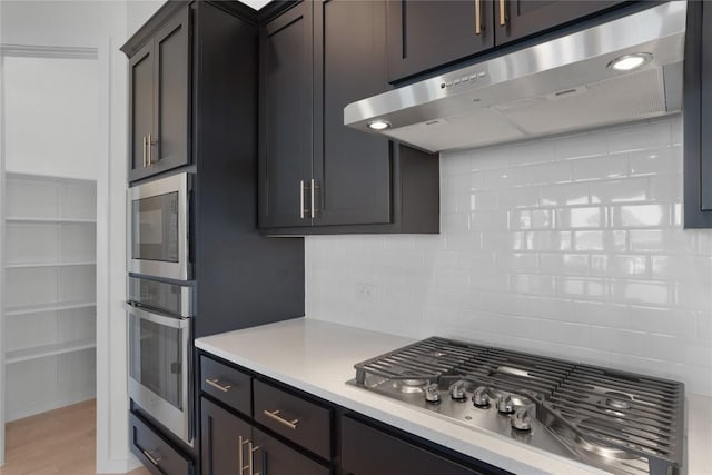 kitchen with decorative backsplash, dark brown cabinets, stainless steel appliances, and light hardwood / wood-style floors