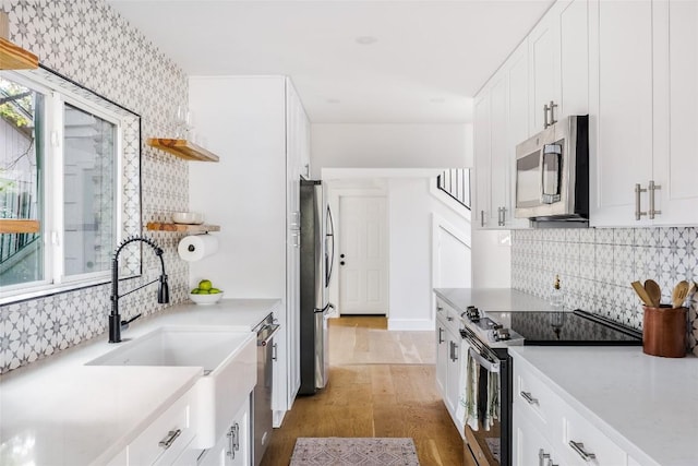 kitchen with white cabinetry, sink, stainless steel appliances, and hardwood / wood-style flooring