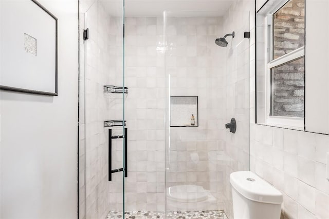 bathroom featuring toilet, tile walls, and a shower with shower door