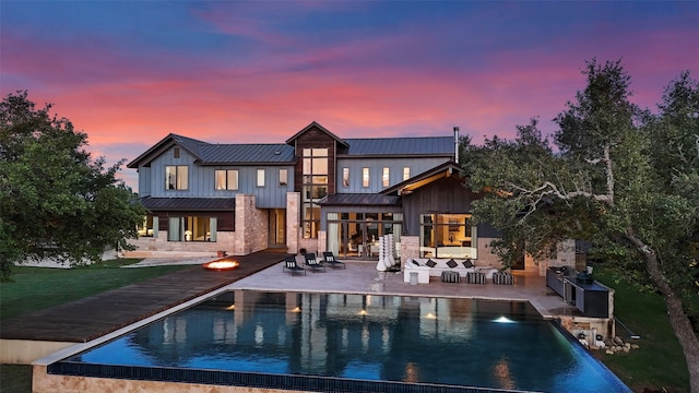 back house at dusk with outdoor lounge area and a patio