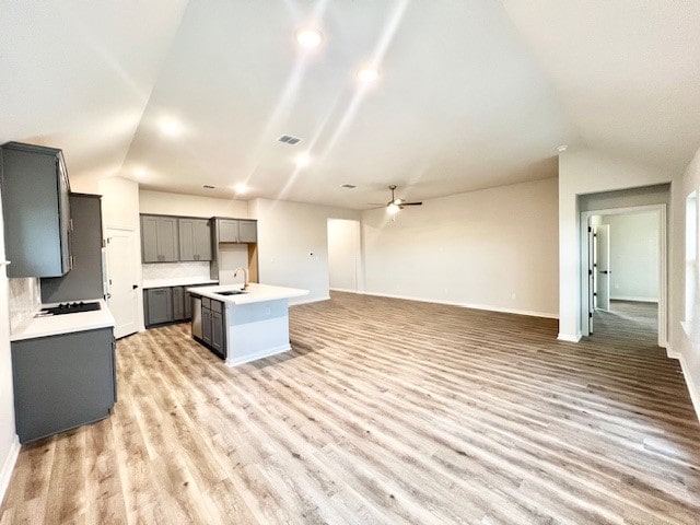 kitchen with light hardwood / wood-style flooring, gray cabinetry, vaulted ceiling, and a center island