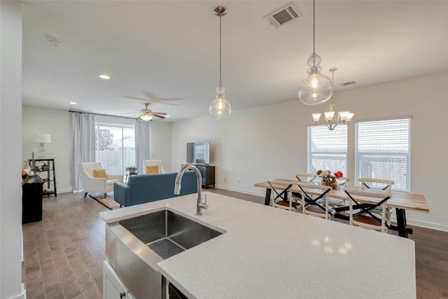 kitchen with sink, dark hardwood / wood-style floors, ceiling fan with notable chandelier, and decorative light fixtures