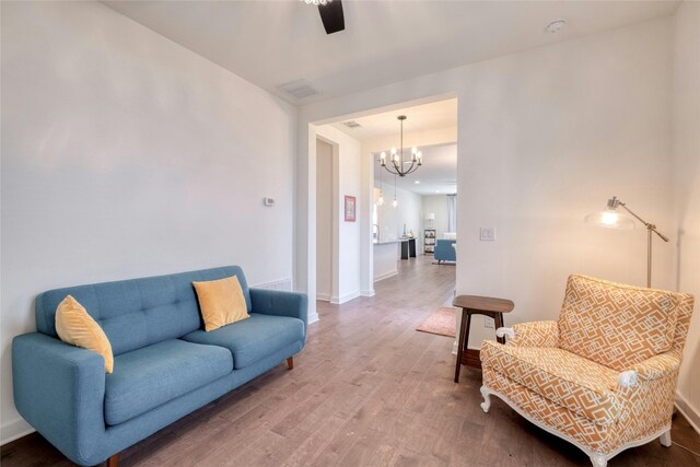 living room featuring ceiling fan with notable chandelier and hardwood / wood-style floors