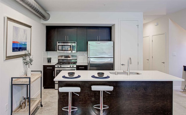 kitchen featuring a kitchen breakfast bar, a sink, an island with sink, stainless steel appliances, and light countertops