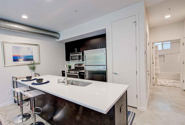 kitchen featuring baseboards, stainless steel appliances, a breakfast bar, and light countertops