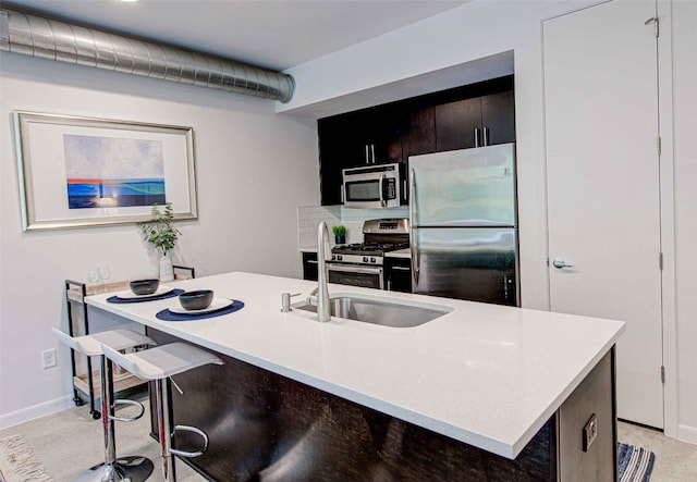 kitchen featuring a kitchen breakfast bar, stainless steel appliances, a kitchen island with sink, and backsplash