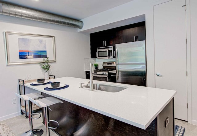 kitchen featuring light countertops, backsplash, baseboards, and stainless steel appliances