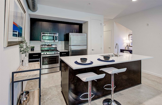 kitchen featuring appliances with stainless steel finishes, sink, a kitchen bar, decorative backsplash, and a center island with sink