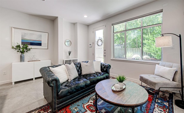 living area featuring plenty of natural light, baseboards, recessed lighting, and concrete flooring