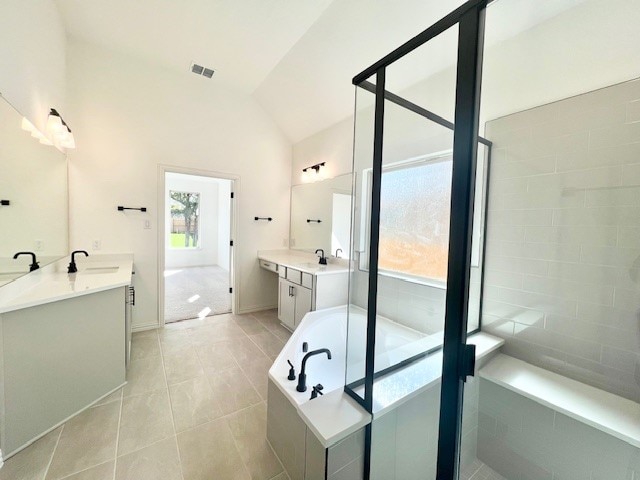 bathroom featuring vanity, independent shower and bath, tile patterned floors, and vaulted ceiling