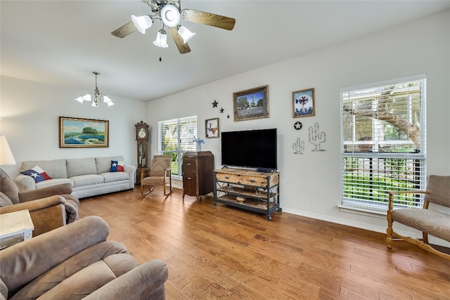 living room with ceiling fan with notable chandelier and wood-type flooring