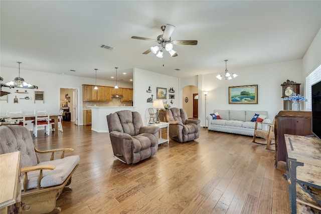 living room with light wood-type flooring and ceiling fan with notable chandelier