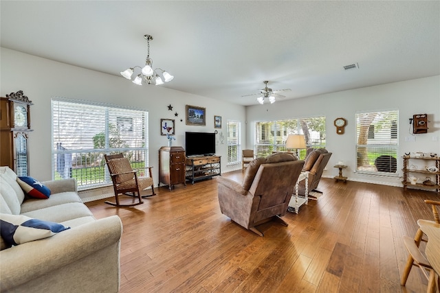 living room with plenty of natural light, ceiling fan with notable chandelier, and hardwood / wood-style flooring