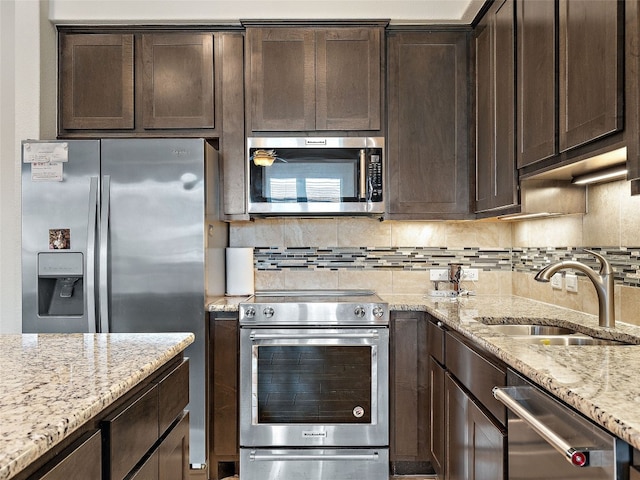 kitchen with dark brown cabinetry, appliances with stainless steel finishes, tasteful backsplash, and sink