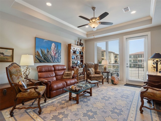 living room with a tray ceiling, crown molding, ceiling fan, and light hardwood / wood-style floors