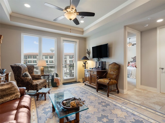 living room with ceiling fan, a raised ceiling, and ornamental molding