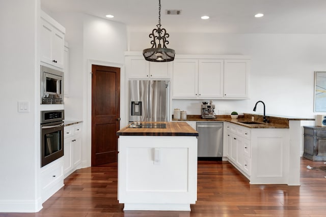 kitchen with wooden counters, decorative light fixtures, sink, white cabinets, and stainless steel appliances