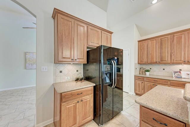 kitchen with backsplash, light tile patterned floors, ceiling fan, and black refrigerator with ice dispenser