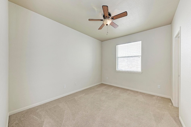 spare room with ceiling fan and light carpet