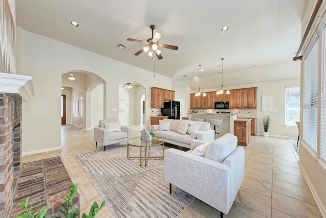 living room with ceiling fan, light tile patterned floors, and a brick fireplace