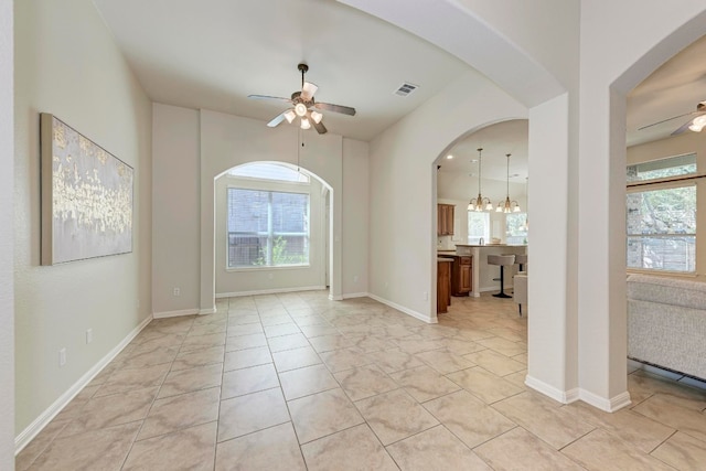 unfurnished room featuring ceiling fan with notable chandelier and light tile patterned floors