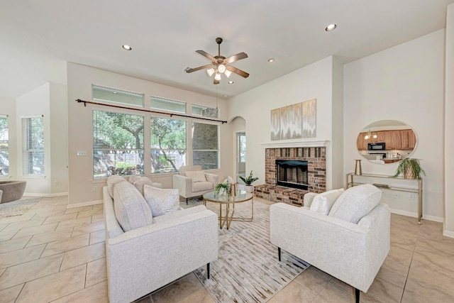 tiled living room with ceiling fan and a fireplace