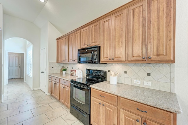 kitchen featuring backsplash, light tile patterned floors, black appliances, light stone counters, and vaulted ceiling