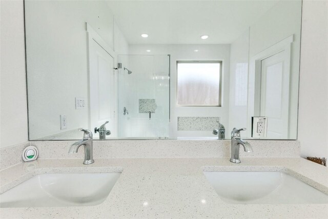 bathroom featuring a shower with door and vanity