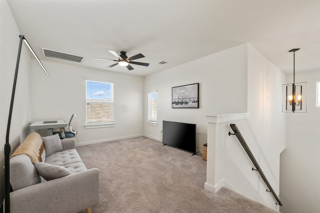 carpeted living room featuring ceiling fan with notable chandelier