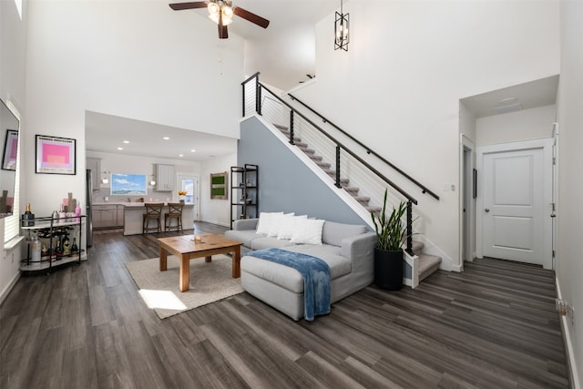 living room with ceiling fan, dark hardwood / wood-style flooring, and a high ceiling