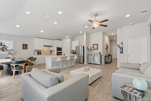 living room with light wood-type flooring, ceiling fan, and vaulted ceiling