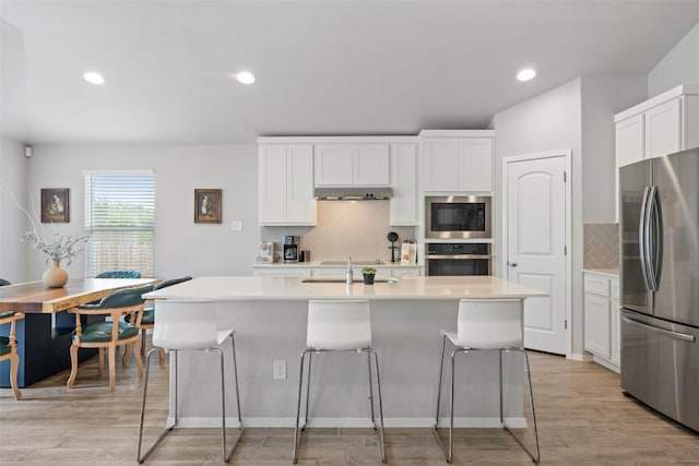 kitchen featuring a center island with sink, stainless steel appliances, and white cabinetry