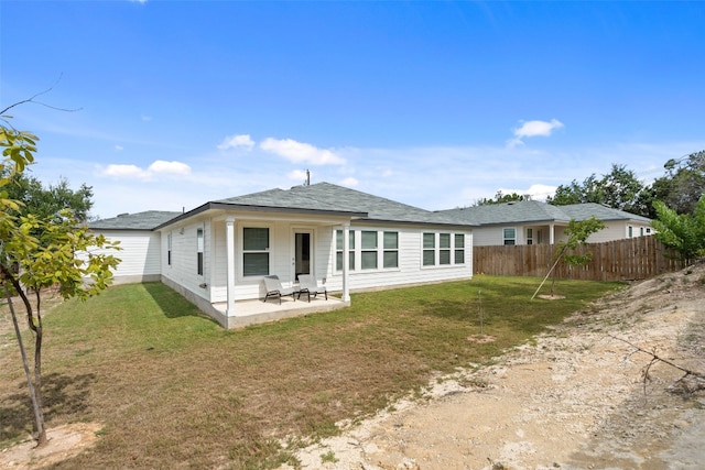 back of property with a lawn and a patio